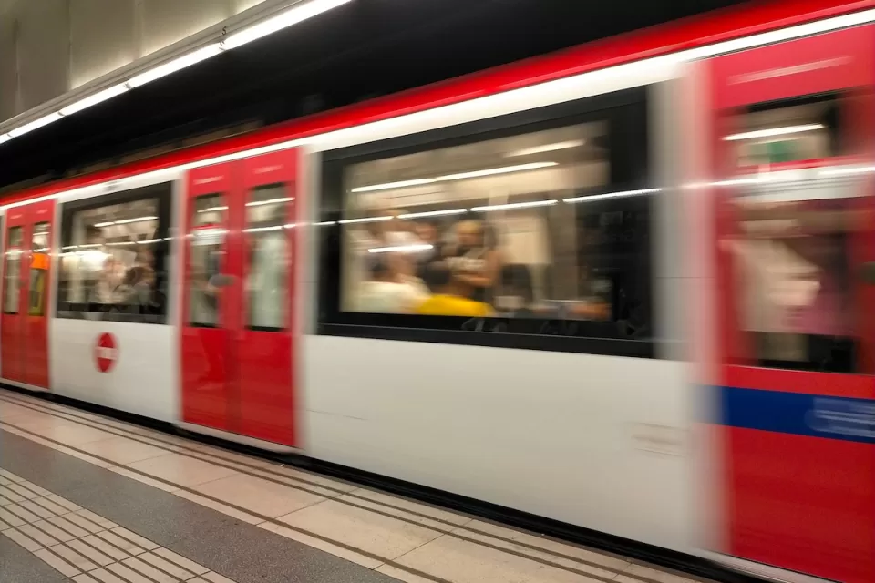 Red and white Barcelona Metro train passing through station.